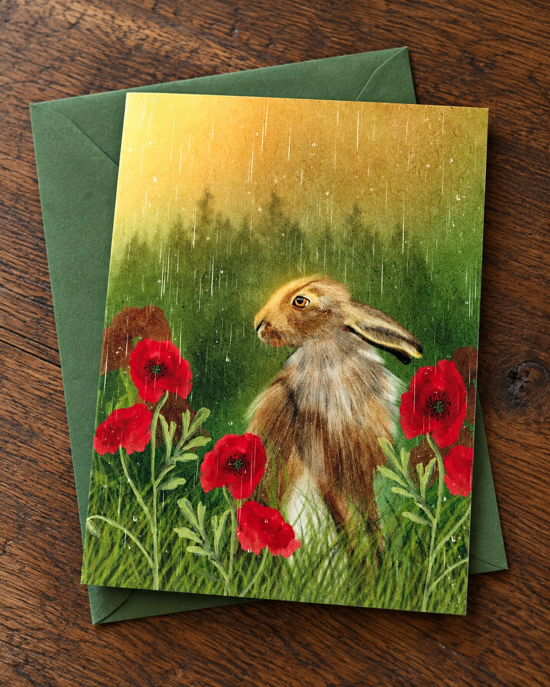 Hare in the Poppies borderless 5 × 7 inch greeting card on a green envelope on an oak desk